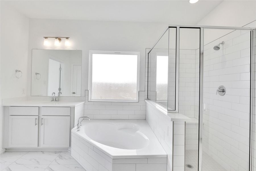 Full bathroom featuring a stall shower, vanity, a bath, and light marble finish flooring Full bathroom featuring a stall shower, vanity, a bath, and light marble finish flooring