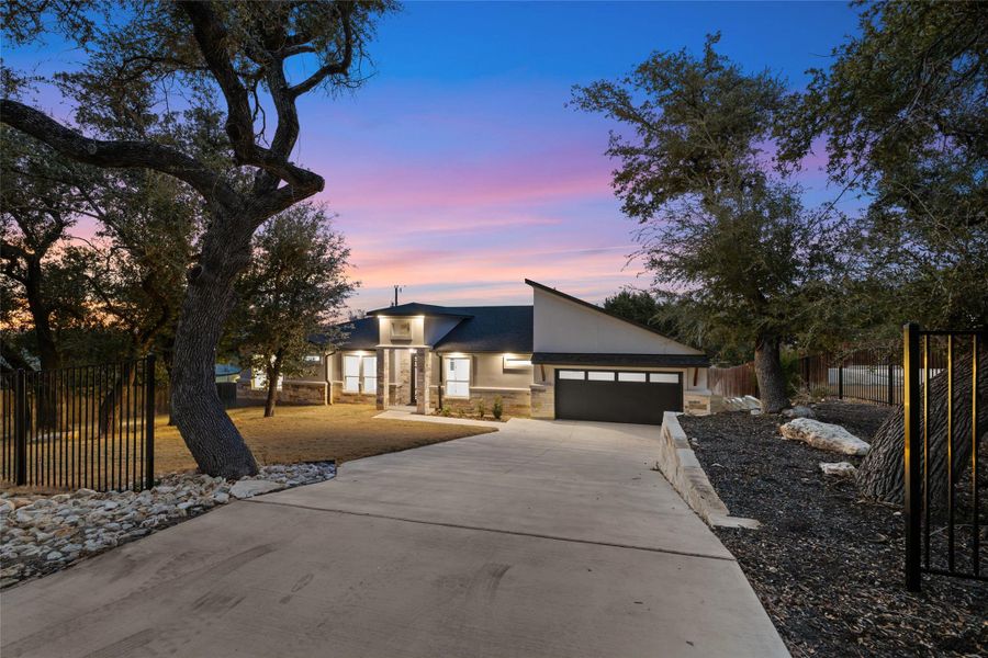 View of front of home featuring stone siding, driveway, stucco siding, and a garage