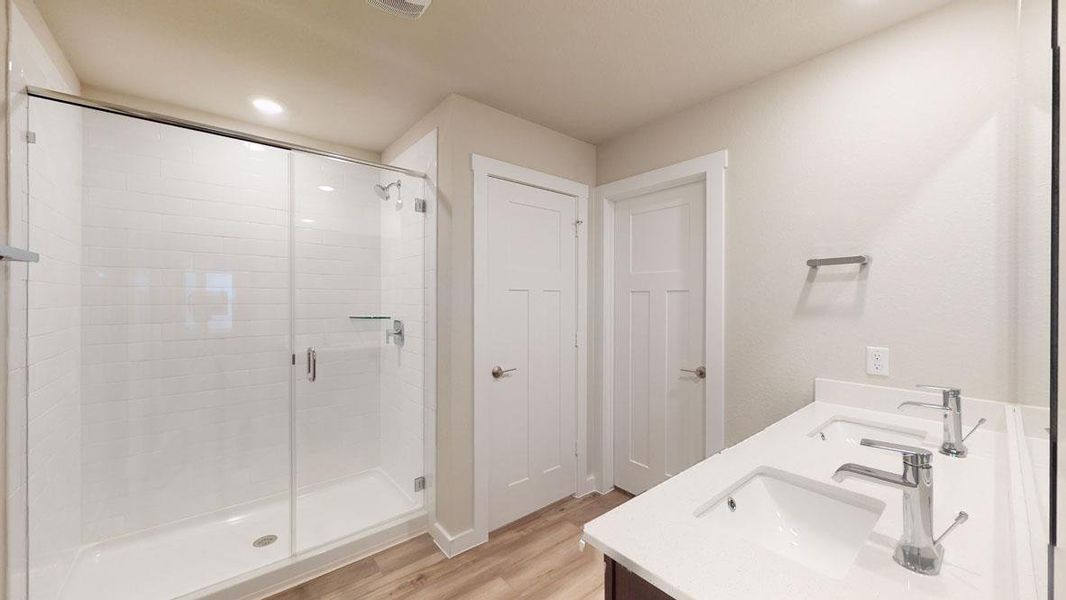 A well-appointed bath boasts dual vanities and a sleek glass-enclosed shower. A well-appointed bath boasts dual vanities and a sleek glass-enclosed shower.