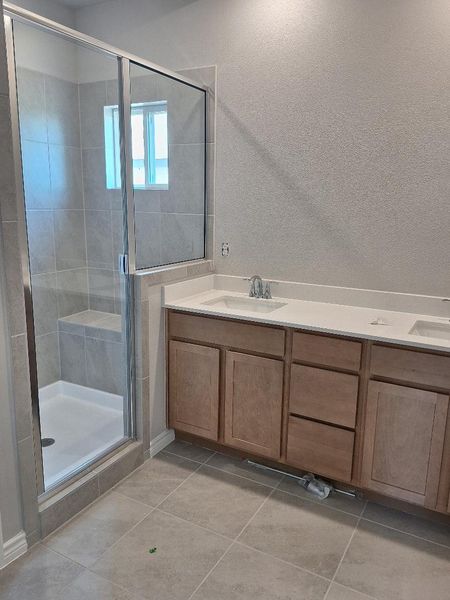 Full bath with a stall shower, tile patterned flooring, and double vanity