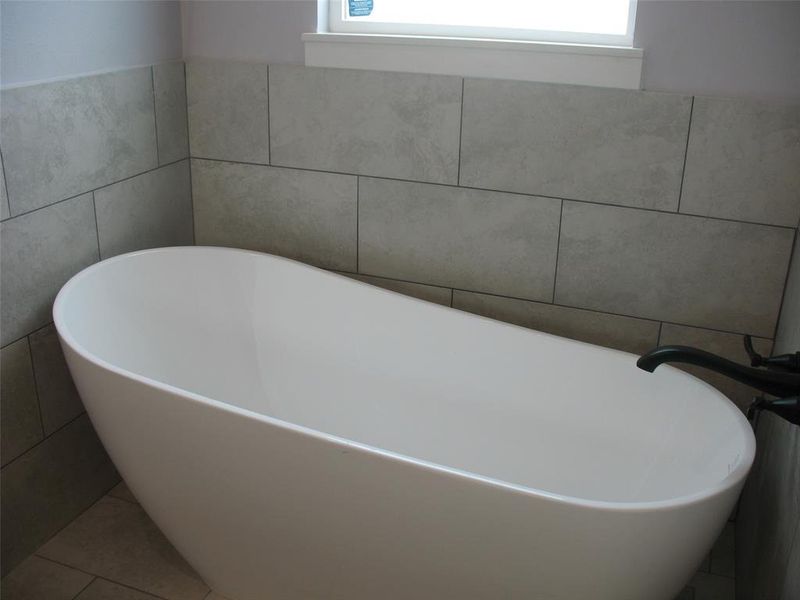 Bathroom with tile walls, a freestanding bath, and tile patterned flooring