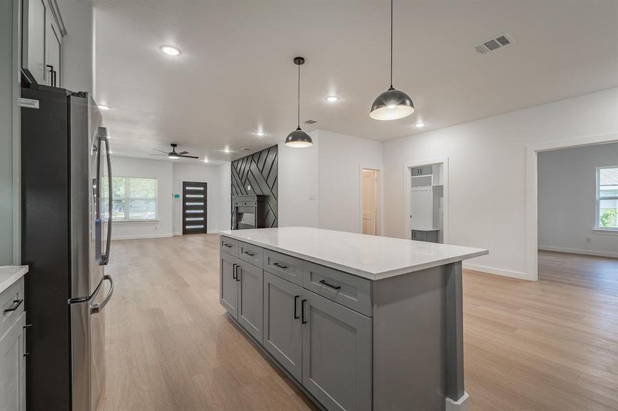 Kitchen with freestanding refrigerator, gray cabinetry, open floor plan, light wood-type flooring, and recessed lighting Kitchen with freestanding refrigerator, gray cabinetry, open floor plan, light wood-type flooring, and recessed lighting