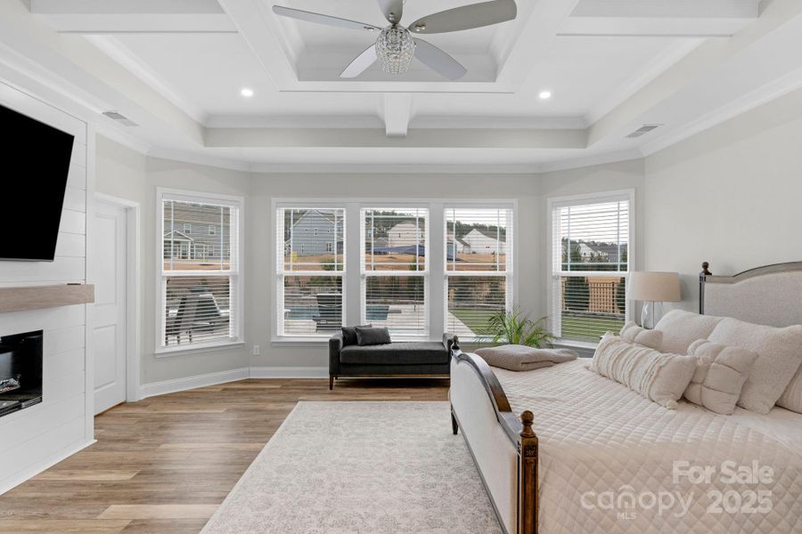 Primary bedroom with custom electric fireplace and coffered ceiling