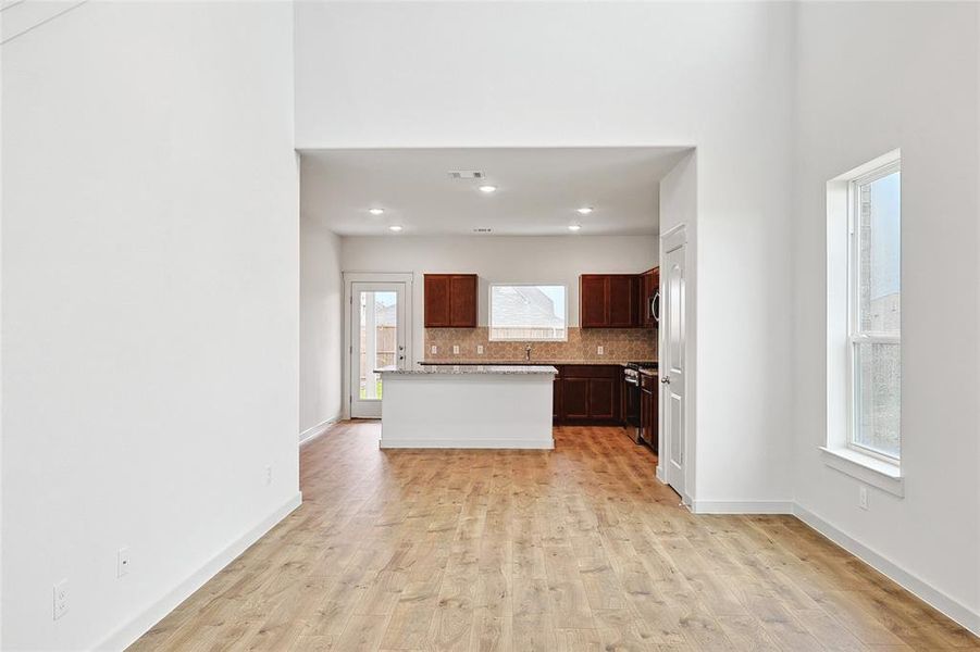 Kitchen featuring sink, tasteful backsplash, a kitchen island, light hardwood / wood-style floors, and gas stove