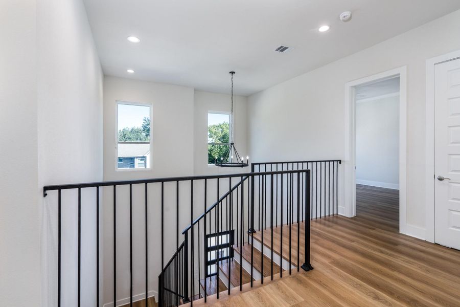 Modern upper-level landing with sleek railings and stylish hanging light fixture. Modern upper-level landing with sleek railings and stylish hanging light fixture.