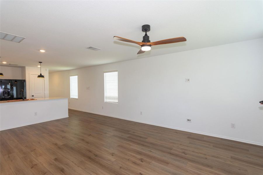 Bright living room featuring wood-finish flooring and a contemporary ceiling fan with integrated lighting