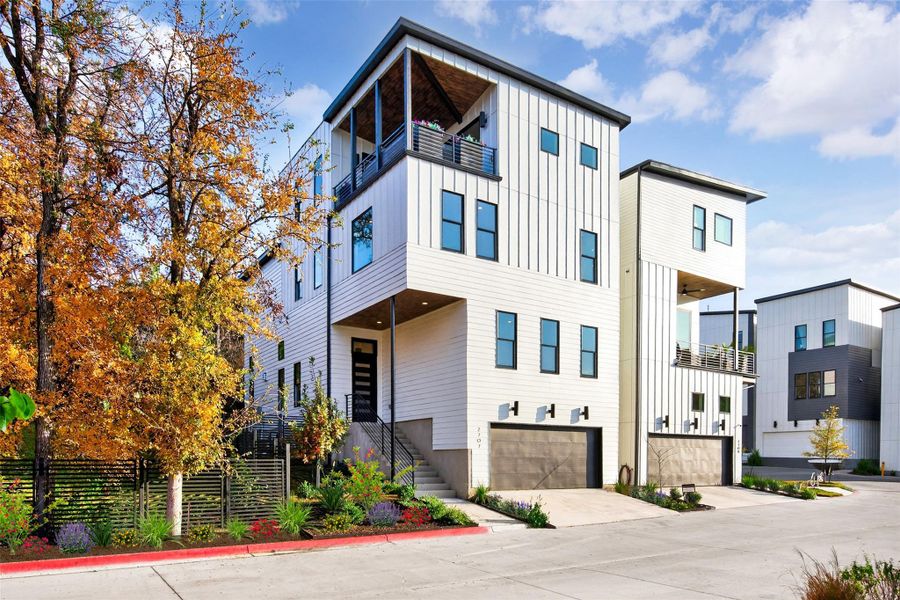 Modern home featuring board and batten siding, a balcony, driveway, an attached garage, and stairs