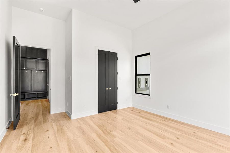Bright room featuring light wood-finish flooring, crisp white walls, and high ceilings