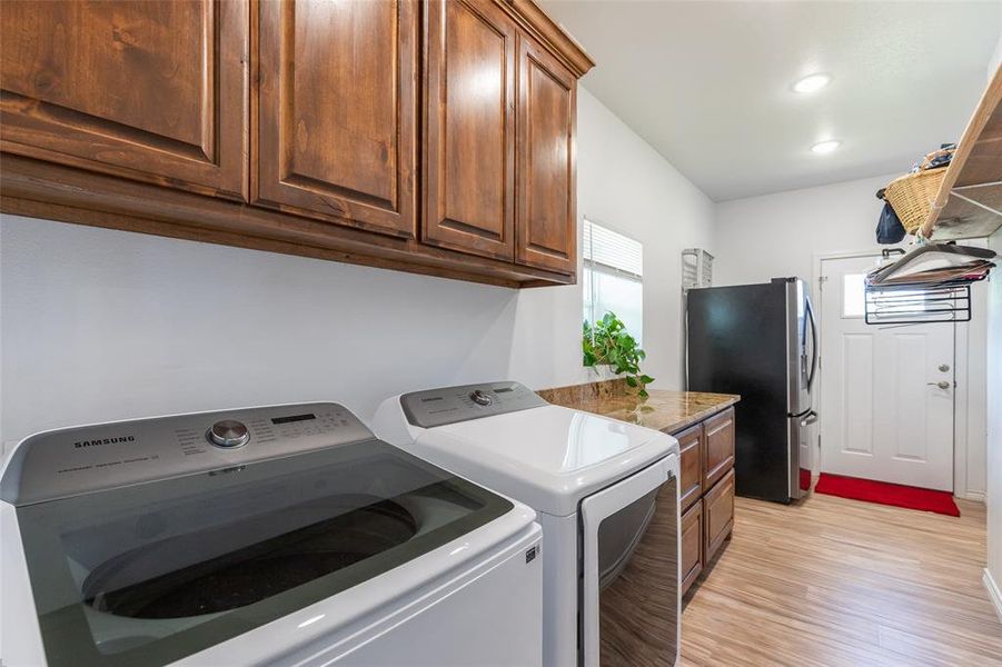 Utility room featuring wood-finish flooring, ample cabinetry, and a countertop workspace Utility room featuring wood-finish flooring, ample cabinetry, and a countertop workspace