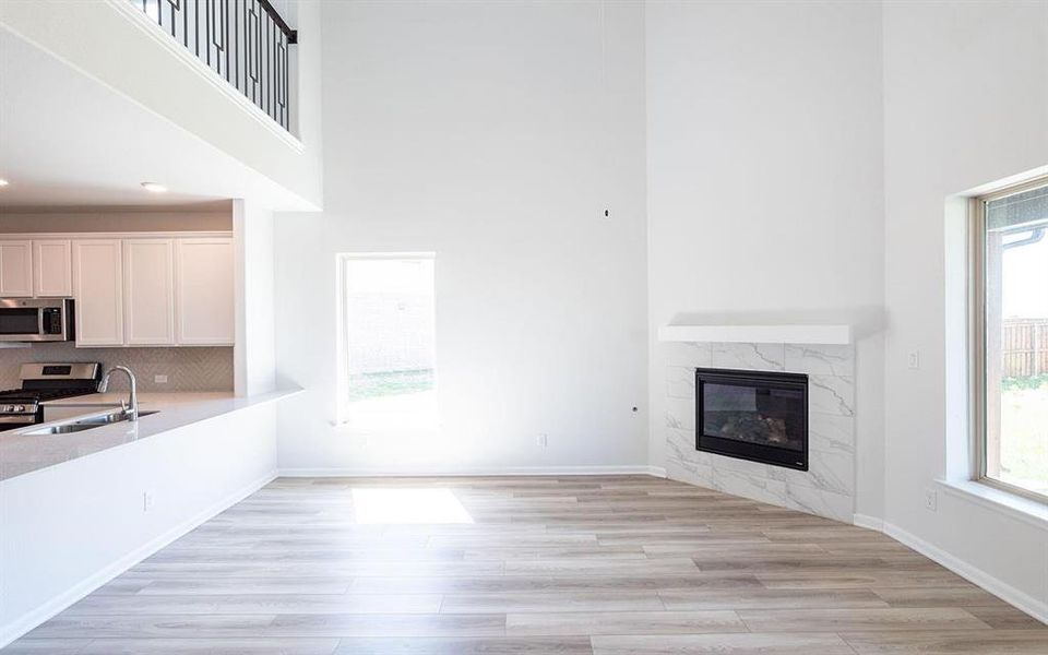 Living room featuring a fireplace, light hardwood / wood-style flooring, sink, and a healthy amount of sunlight