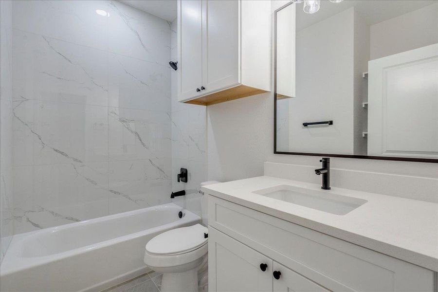 Refined additional bathroom with a sleek white vanity, integrated sink, and sophisticated dark hardware.