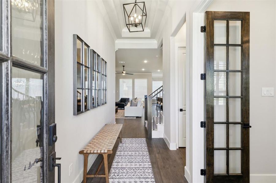 Hallway with french doors, dark hardwood / wood-style flooring, an inviting chandelier, and ornamental molding