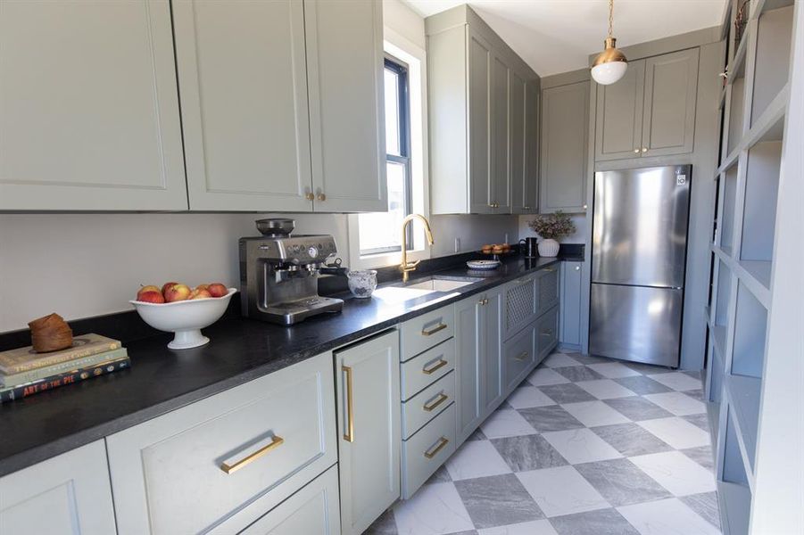 Kitchen with freestanding refrigerator, dark countertops, gray cabinetry, light flooring, and pendant lighting