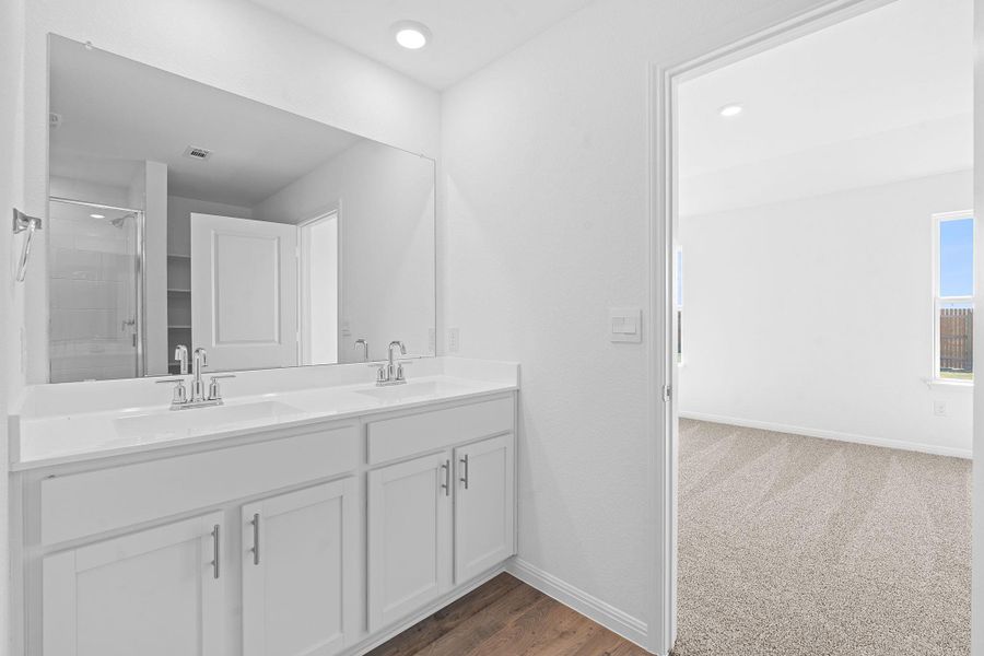 Full bathroom with a shower stall, double vanity, recessed lighting, dark carpet, and dark wood-style flooring