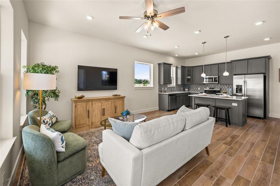 Open-concept living space featuring wood-look tile flooring, recessed lighting, and a ceiling fan