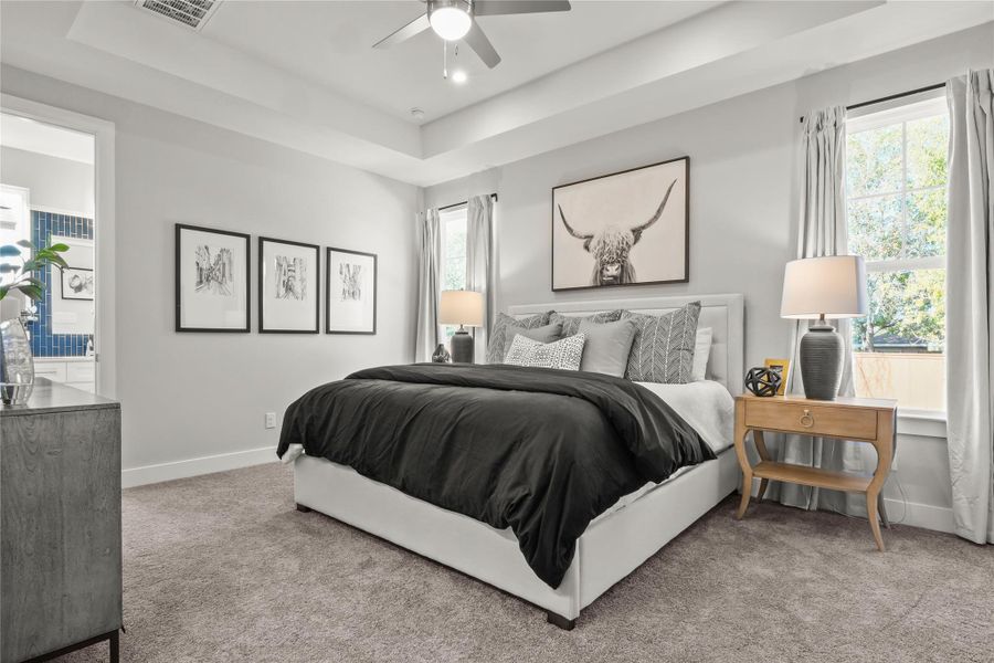 Bedroom featuring carpet, a raised ceiling, and a ceiling fanThe photos shown are of a completed home with the same floor plan and may not reflect the exact finishes, features, or layout of the home currently under construction. Actual details may vary. Please contact the builder or listing agent for specific information about this property.