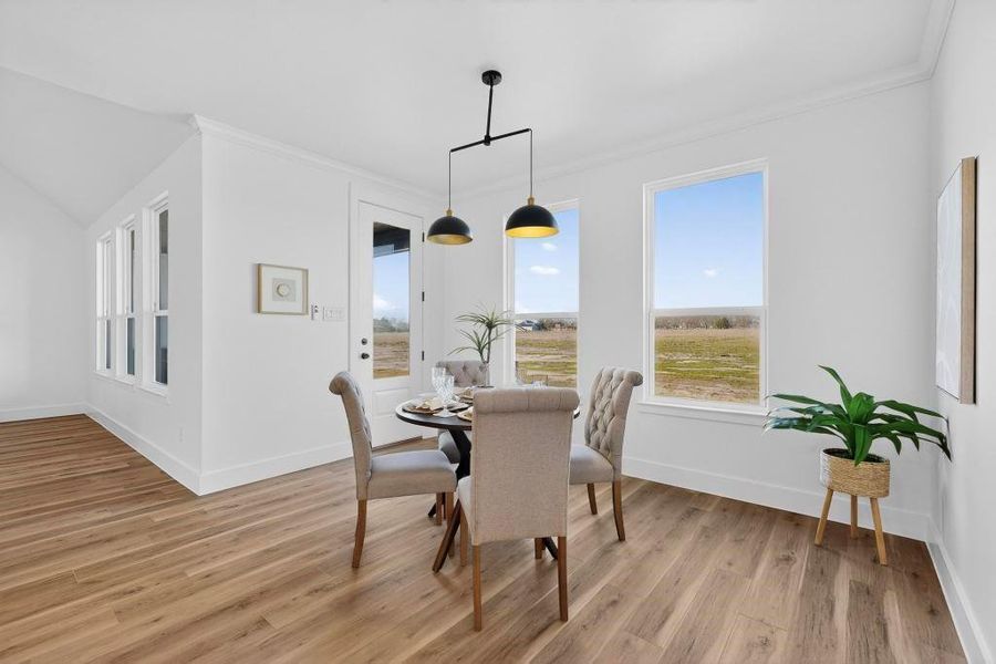 Dining room with ornamental molding and light wood-style flooring Dining room with ornamental molding and light wood-style flooring