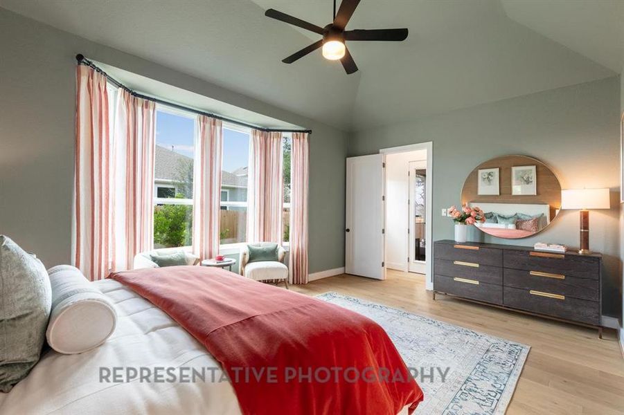 Bedroom featuring light wood-style flooring, lofted ceiling, and a ceiling fan