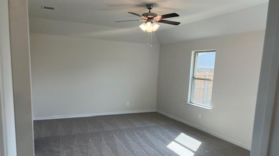 Carpeted spare room featuring vaulted ceiling and ceiling fan Carpeted spare room featuring vaulted ceiling and ceiling fan