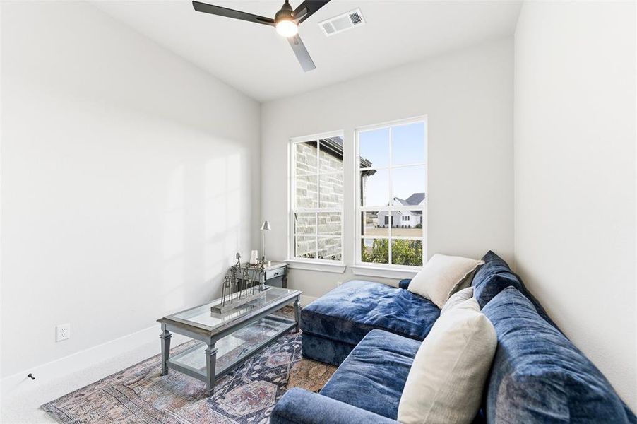 Carpeted living area with baseboards and a ceiling fan
