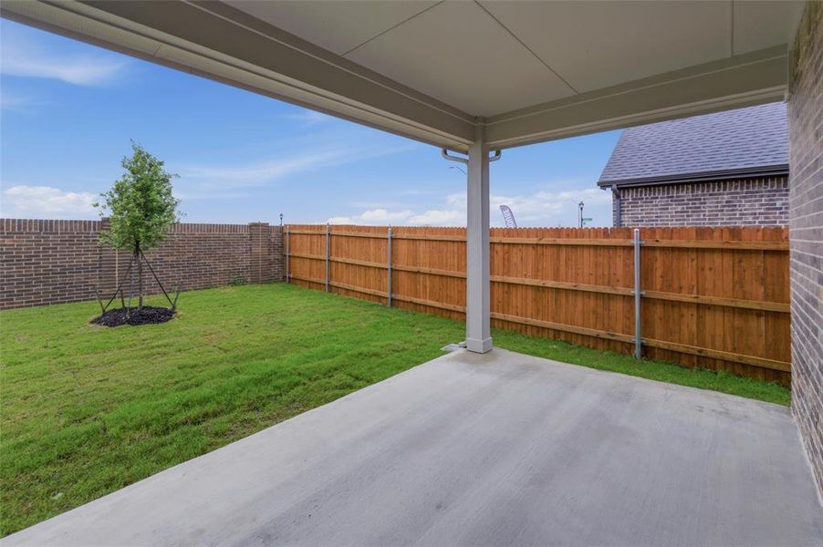 Covered patio with a concrete surface, overlooking a grassy yard