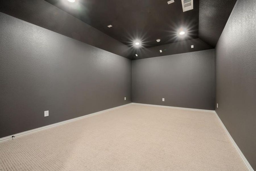 Carpeted home theater room with visible vents, recessed lighting, baseboards, and vaulted ceiling