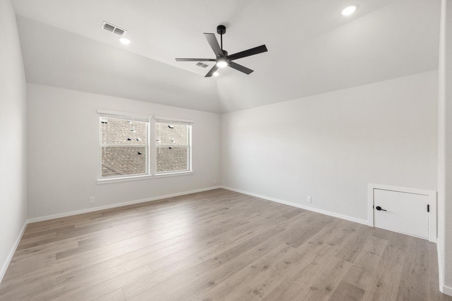Empty bedroom with vaulted ceiling, black ceiling fan, and light wood floors Empty bedroom with vaulted ceiling, black ceiling fan, and light wood floors