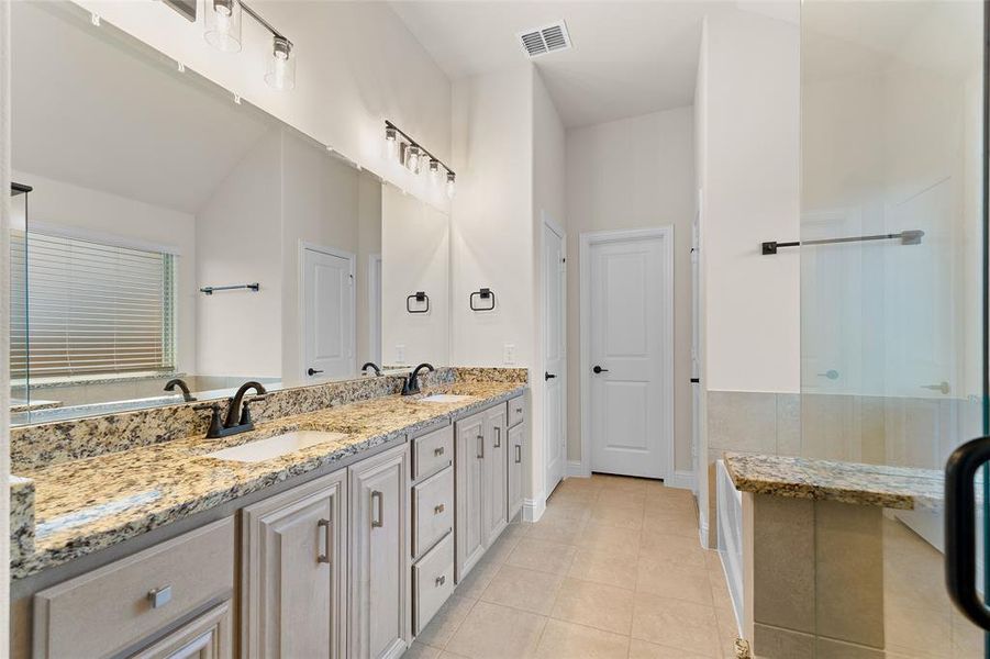 Full bath featuring double vanity, light tile patterned floors, and a shower with door Full bath featuring double vanity, light tile patterned floors, and a shower with door