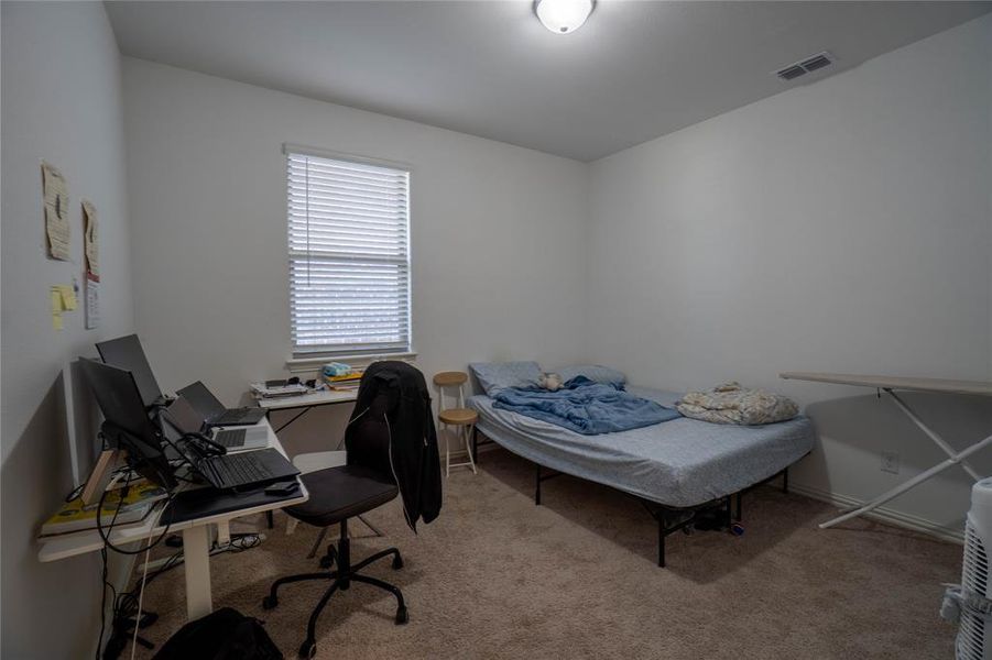 Light-filled room featuring neutral carpet flooring, a single window with horizontal blinds, and a flush-mount ceiling light fixture