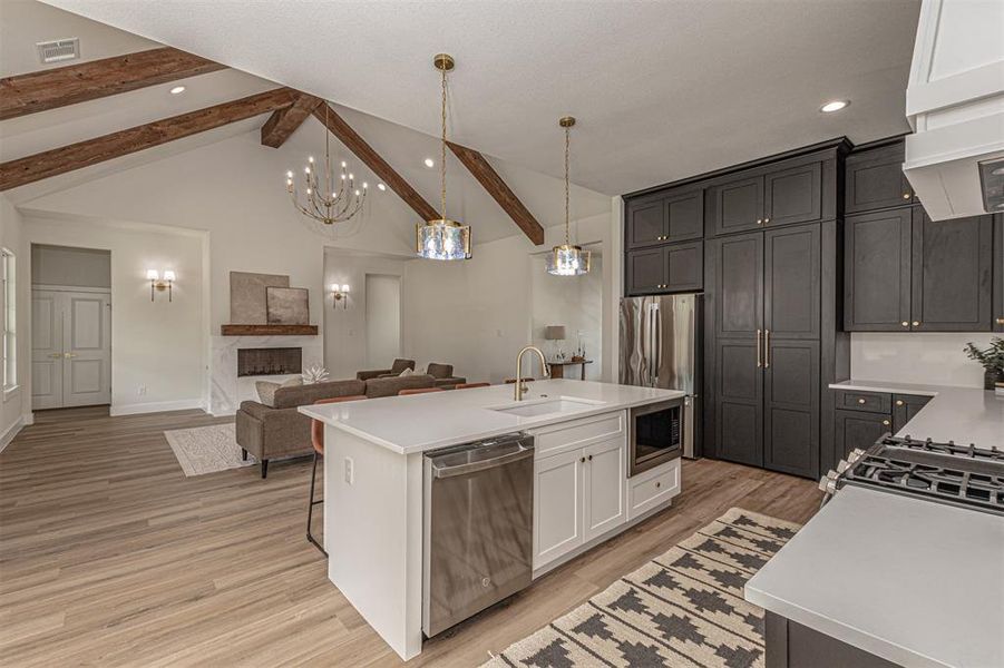 Open-concept kitchen and living area featuring vaulted ceilings with exposed wood beams
