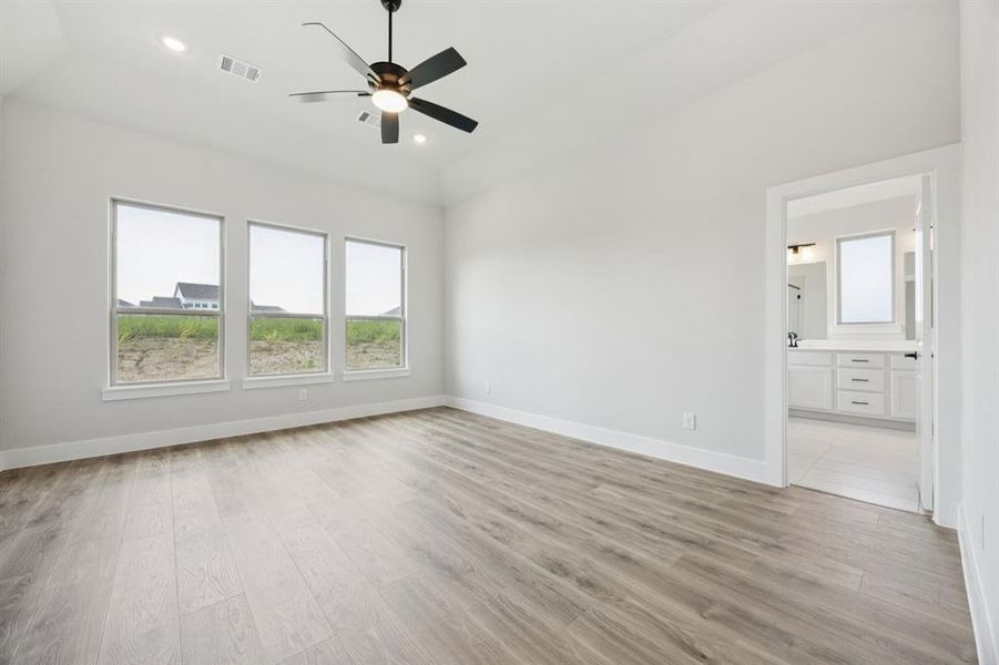 Unfurnished bedroom featuring light wood finished floors, a ceiling fan, recessed lighting, and ensuite bath