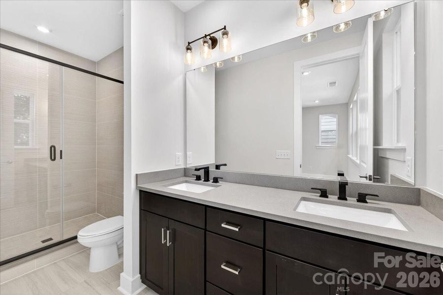 Dual vanity primary bathroom with tiled walk-in shower
