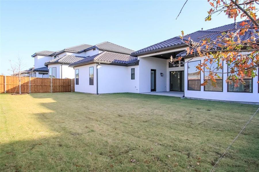 Rear view of property with a lawn and a patio