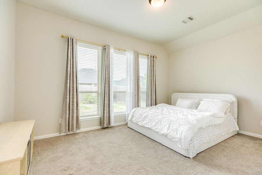 Spacious primary bedroom with ample room, featuring three large windows that offer views of the backyard. The room boasts great carpeting. Spacious primary bedroom with ample room, featuring three large windows that offer views of the backyard. The room boasts great carpeting.