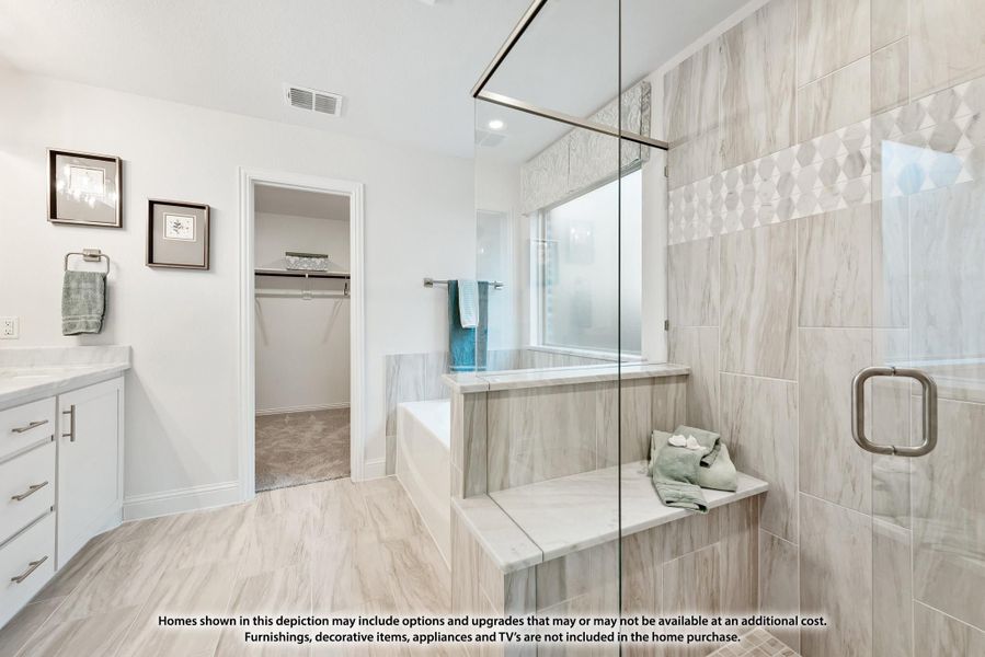 Master bathroom with glass walk-in shower, soaking tub, white vanity, and walk-in closet entrance Master bathroom with glass walk-in shower, soaking tub, white vanity, and walk-in closet entrance