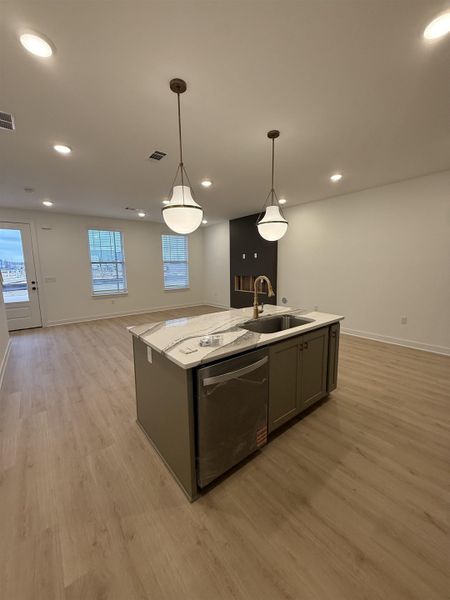 Kitchen featuring open floor plan, a kitchen island with sink, light wood finished floors, and dishwasher