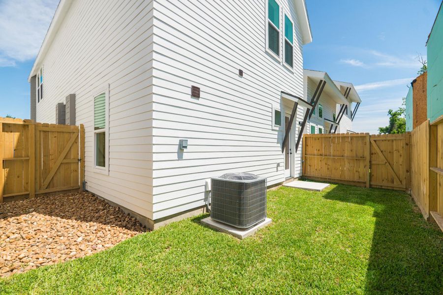 This photo shows the side of a house with white siding, a small grassy yard, and a wooden fence. There's an air conditioning unit and a stone path leading to a back door. The area is well-maintained and receives ample sunlight.Photo Disclaimer: Photos are representative of the community and may depict a similar floor plan, model home, or previously completed residence. This photo shows the side of a house with white siding, a small grassy yard, and a wooden fence. There's an air conditioning unit and a stone path leading to a back door. The area is well-maintained and receives ample sunlight.Photo Disclaimer: Photos are representative of the community and may depict a similar floor plan, model home, or previously completed residence.