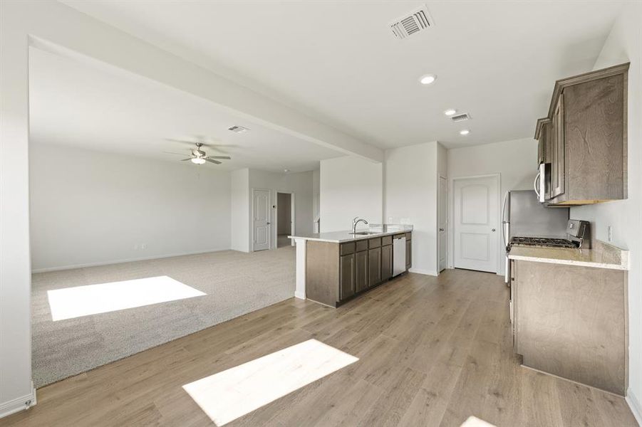Kitchen with recessed lighting, ceiling fan, a peninsula, light wood finished floors, and light stone counters Kitchen with recessed lighting, ceiling fan, a peninsula, light wood finished floors, and light stone counters