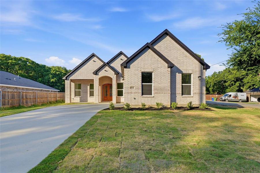 Brick exterior residence featuring a prominent arched entryway with double wooden doors
