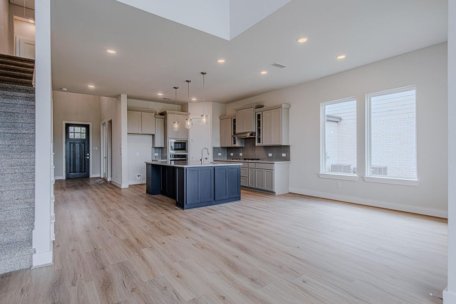 Open-concept living at its finest—this light-filled space features soaring ceilings, warm wood-look flooring, and a seamless flow into the gourmet kitchen. Open-concept living at its finest—this light-filled space features soaring ceilings, warm wood-look flooring, and a seamless flow into the gourmet kitchen.