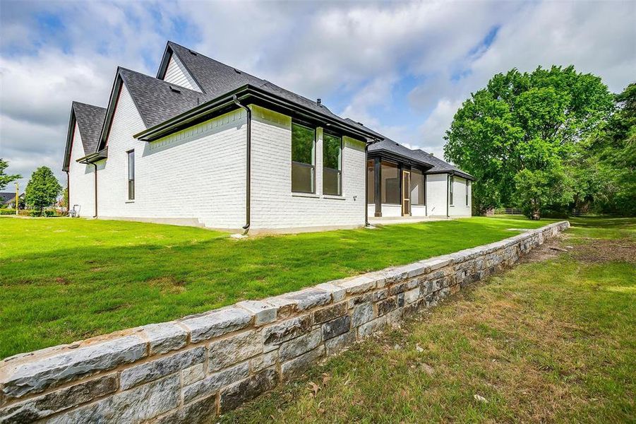 View of side of property featuring a lawn, a sunroom, roof with shingles, and brick siding View of side of property featuring a lawn, a sunroom, roof with shingles, and brick siding