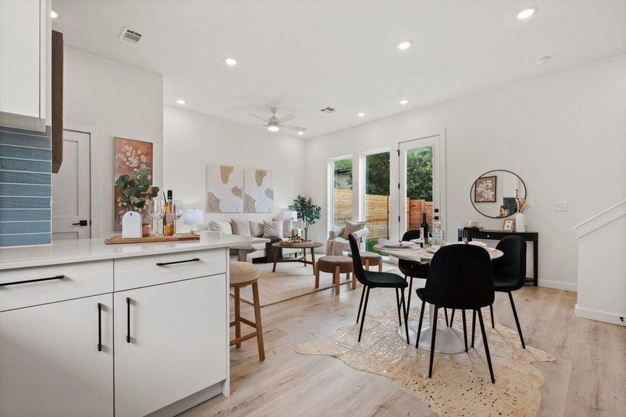 Open concept living area with light-toned flooring, recessed lighting, and large glass paneled doors providing ample natural light