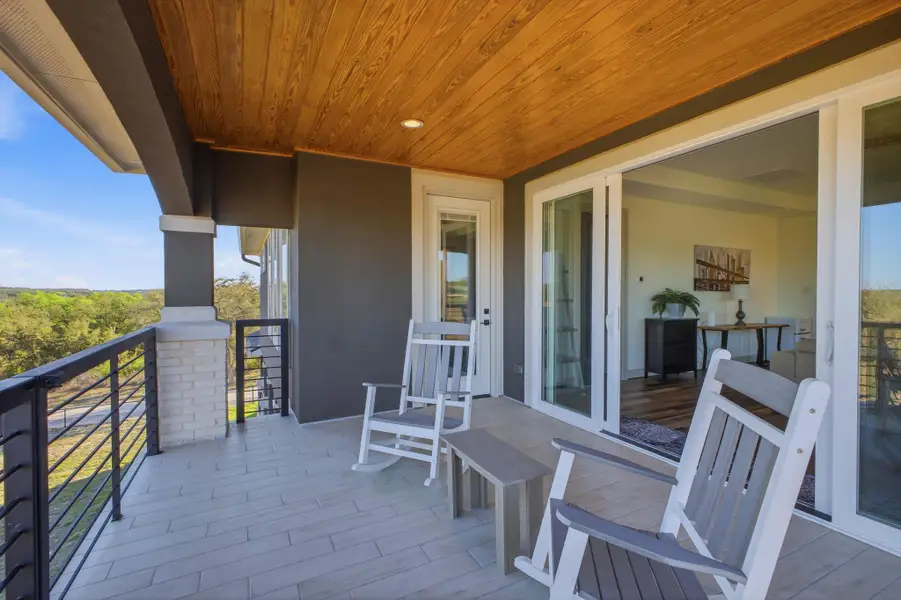 Spacious balcony featuring a wood-paneled ceiling, light-colored floor tiling, and a metal railing