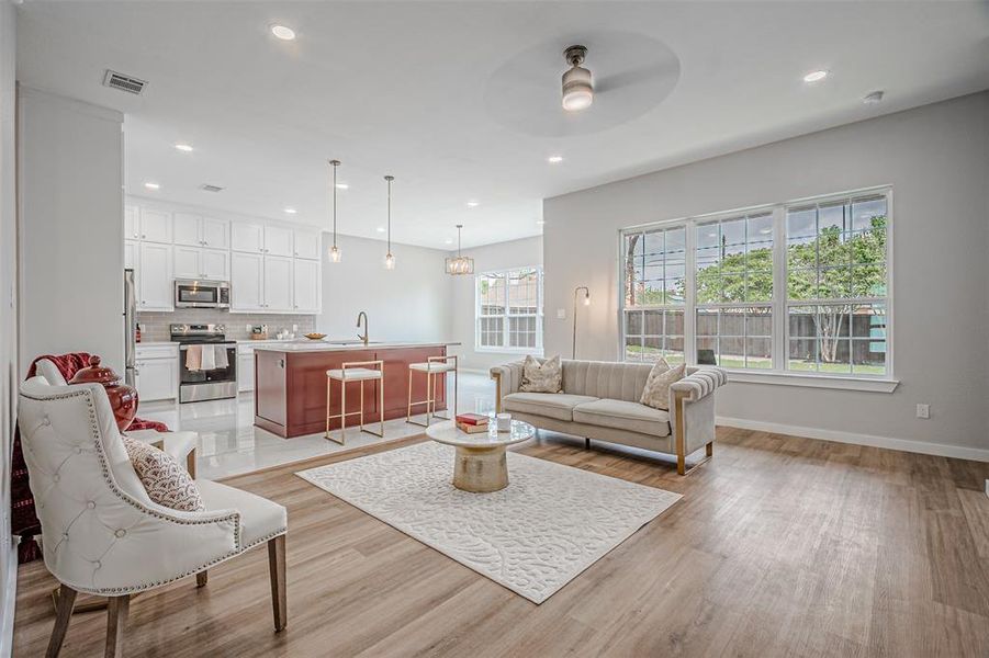 Open-concept living area featuring wood-finish flooring, a contemporary kitchen, and expansive windows