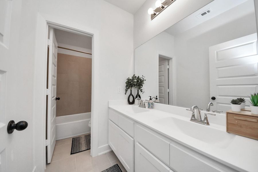This photo shows a modern, bright bathroom featuring a large mirror, dual sinks, and sleek fixtures. The room has a neutral color palette, with a door leading to a tiled bathtub area. The space is enhanced by contemporary decor and ample lighting. This photo shows a modern, bright bathroom featuring a large mirror, dual sinks, and sleek fixtures. The room has a neutral color palette, with a door leading to a tiled bathtub area. The space is enhanced by contemporary decor and ample lighting.