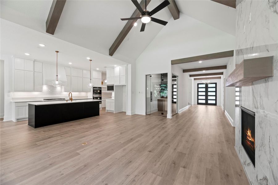 Stunning open-concept living with vaulted ceilings, wood beams, and a seamless flow from the chef’s kitchen to the elegant living room