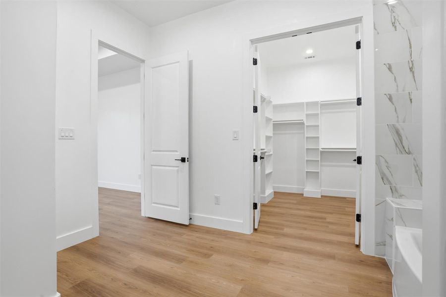 Walk in closet with light wood finished floors