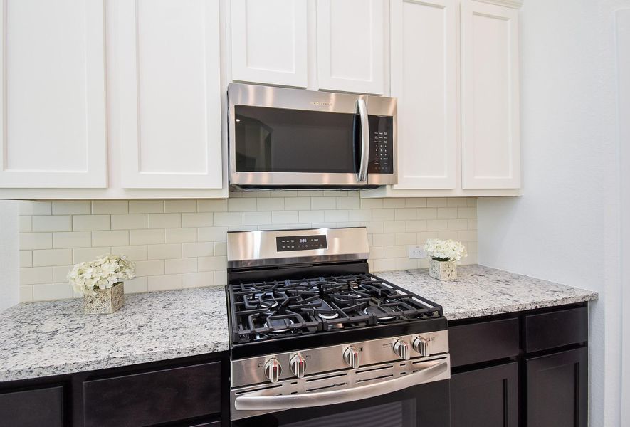 A shining, heavy duty cook top is just the beginning of culinary magic, below a wall of vanilla toned subway styled tile backsplash.