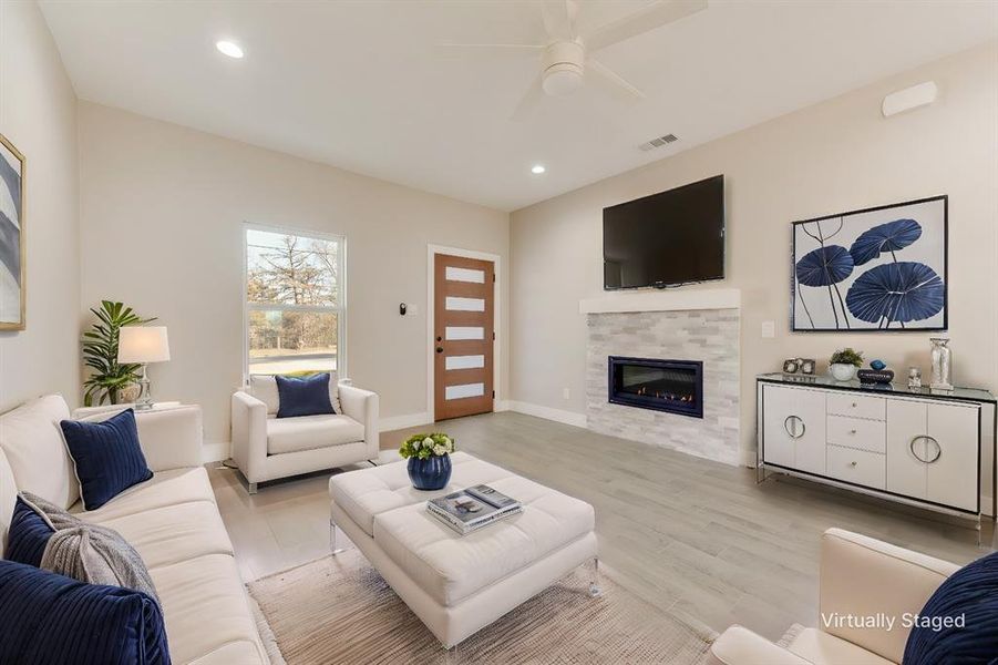 Living room with ceiling fan, a fireplace, and light wood-type flooring