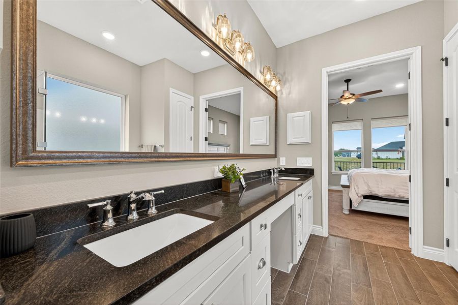 Luxurious bath featuring double vanities with granite counters, framed mirrors, and elegant lighting. Luxurious bath featuring double vanities with granite counters, framed mirrors, and elegant lighting.